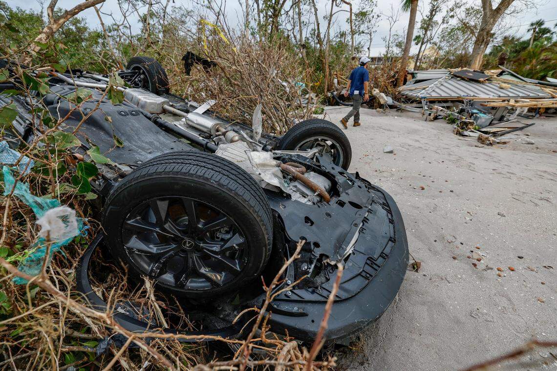 A turned-over car remains embedded in the trees and brush caused by the storm surge from hurricanes Helene and Milton on the barrier island of Manasota Key.
