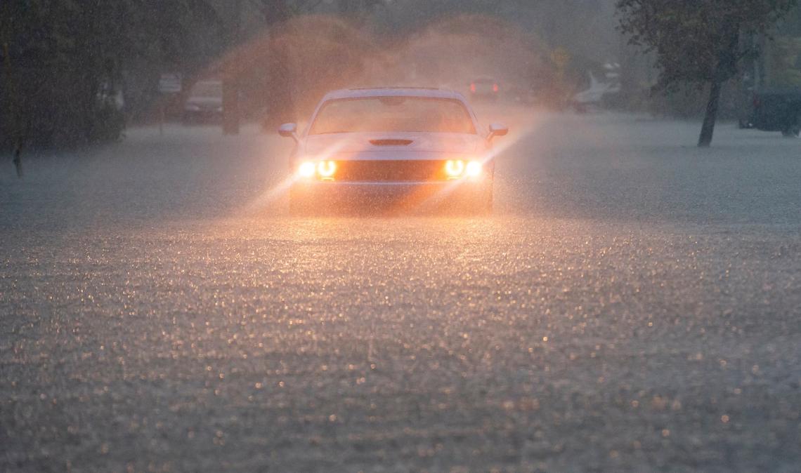 A driver blinks their hazard lights on Arthur Street as heavy rain floods the surrounding neighborhood on Wednesday, June 12, 2024, in Hollywood, Fla.