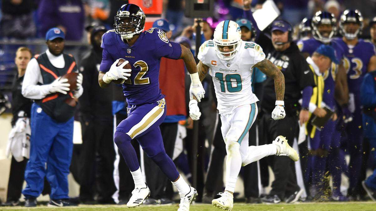 Baltimore Ravens cornerback Jimmy Smith, left, rushes past Miami Dolphins wide receiver Kenny Stills for a touchdown after intercepting a pass attempt in the second half of an NFL football game, Thursday, Oct. 26, 2017, in Baltimore. Baltimore won 40-0. (AP Photo/Gail Burton)