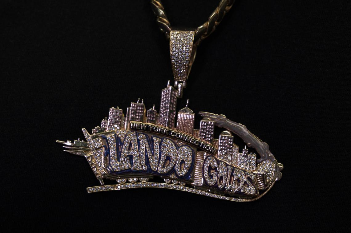 Gold and diamonds pendant bearing the logo of the Lando Golds, one of the oldest shops in Miami to create custom grillz and gold teeth.  