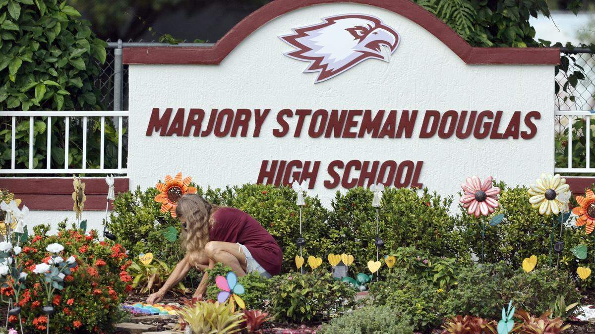 A woman clears debris on June 14, 2024, from a memorial garden at Marjory Stoneman Douglas High School in Parkland. 