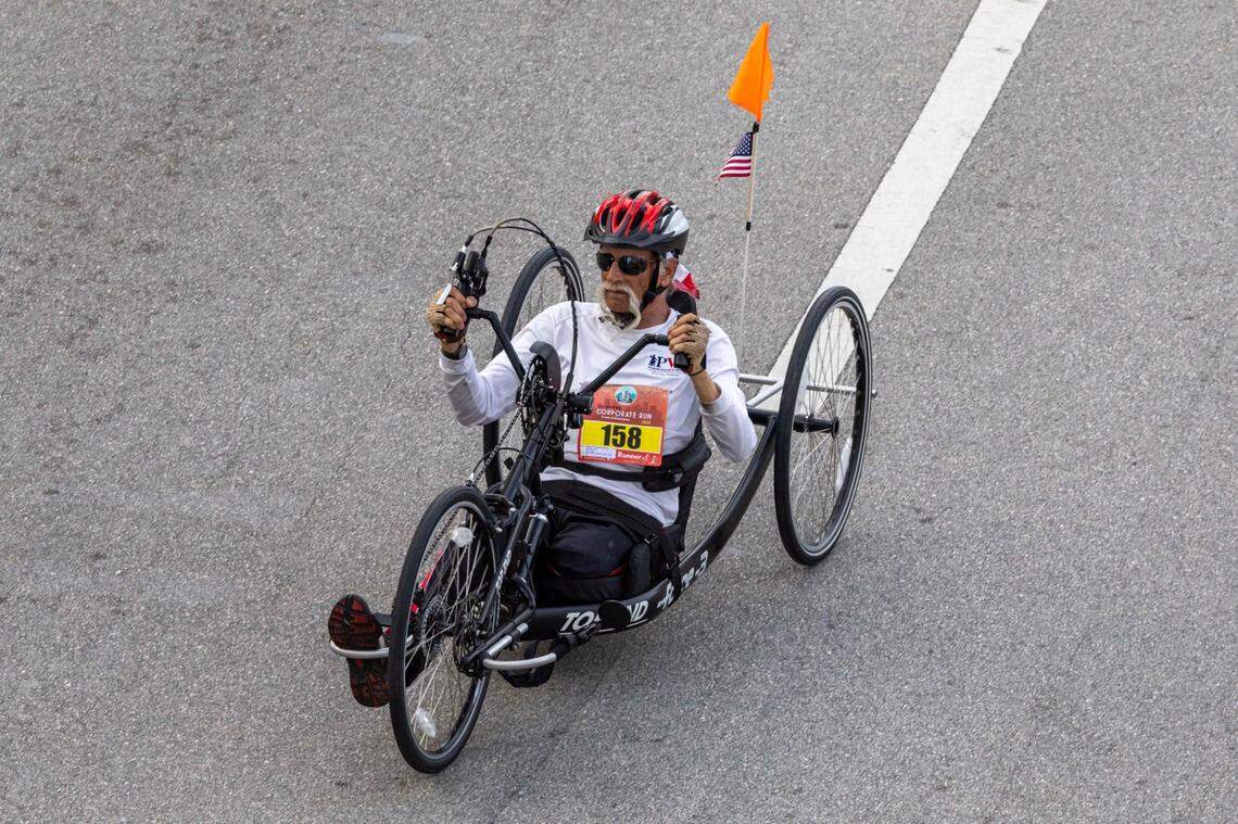 A biker makes his way in front of Bayfront Park on Biscayne Boulevard heading south during the 2025 Lexus Corporate Run on Thursday, April 24, 2025, in Miami, Fla. Over 18,00 runners participated in the 5K race’s 40th anniversary in Downtown Miami.