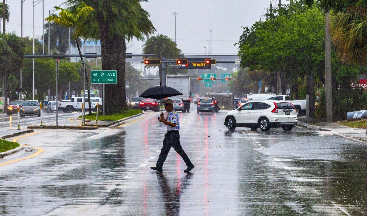 A man crosses 163rd Street in North Miami under heavy rain as a severe weather alert was issued by the National Weather Service on March 22, 2024.