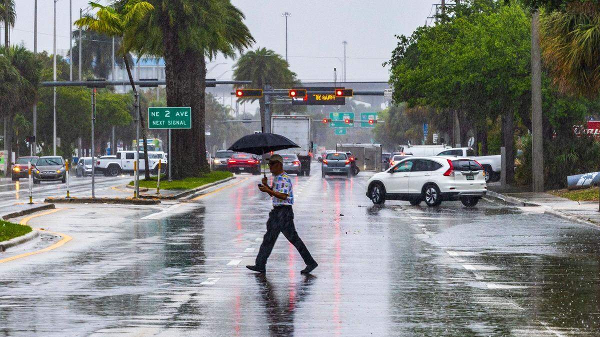 Un hombre cruza 163 Street en North Miami bajo una intensa lluvia mientras el Servicio Nacional del Tiempo emitía una alerta por mal tiempo el 22 de marzo de 2024.
