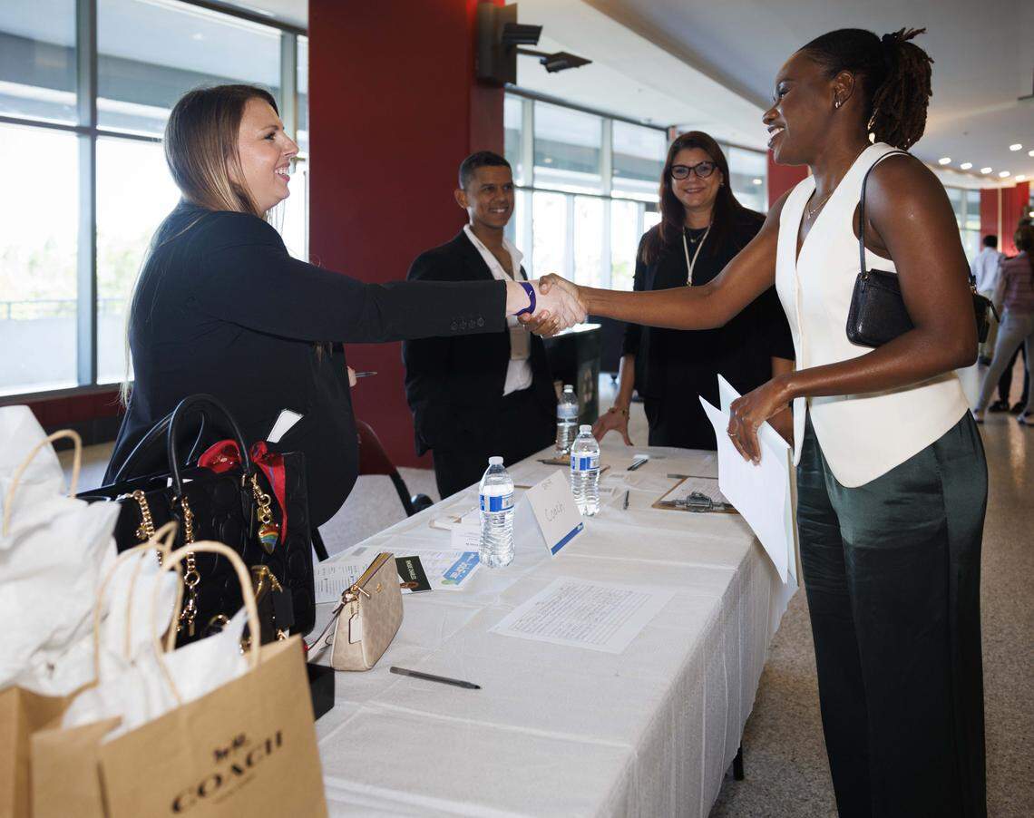 Megan Lucchese, Coach store manager at Sawgrass Mills, left, shakes hands with a potential candidate during the Job News South Florida Job Fair on Thursday, Oct. 30, 2025, at Amerant Bank Arena in Sunrise, Fla.