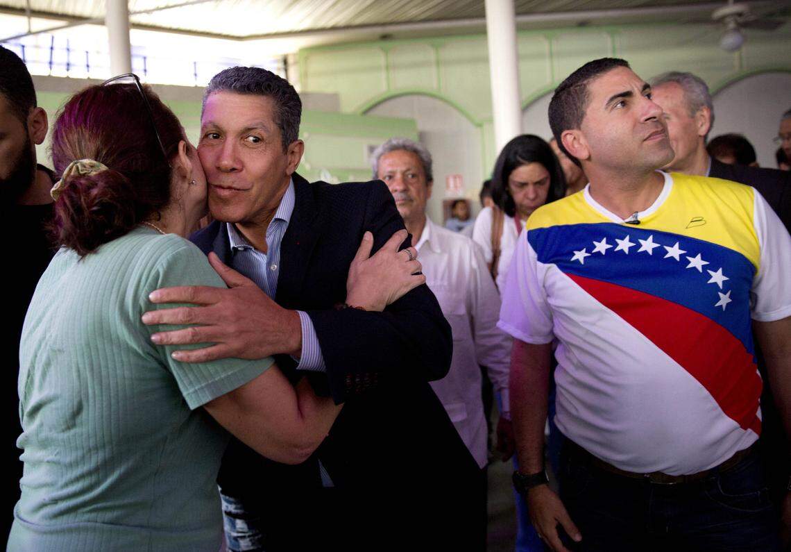 A supporter kisses independent presidential candidate Henri Falcon, second left, as he stands next to independent presidential candidate Luis Ratti, right, in Caracas, Venezuela, Tuesday, May 8, 2018. Ratti withdrew from the electoral contest on Tuesday and announced his support for Falcon, who has established himself as President Nicolas Maduro's main opponent in the presidential elections on May 20. (AP Photo/Ariana Cubillos)
