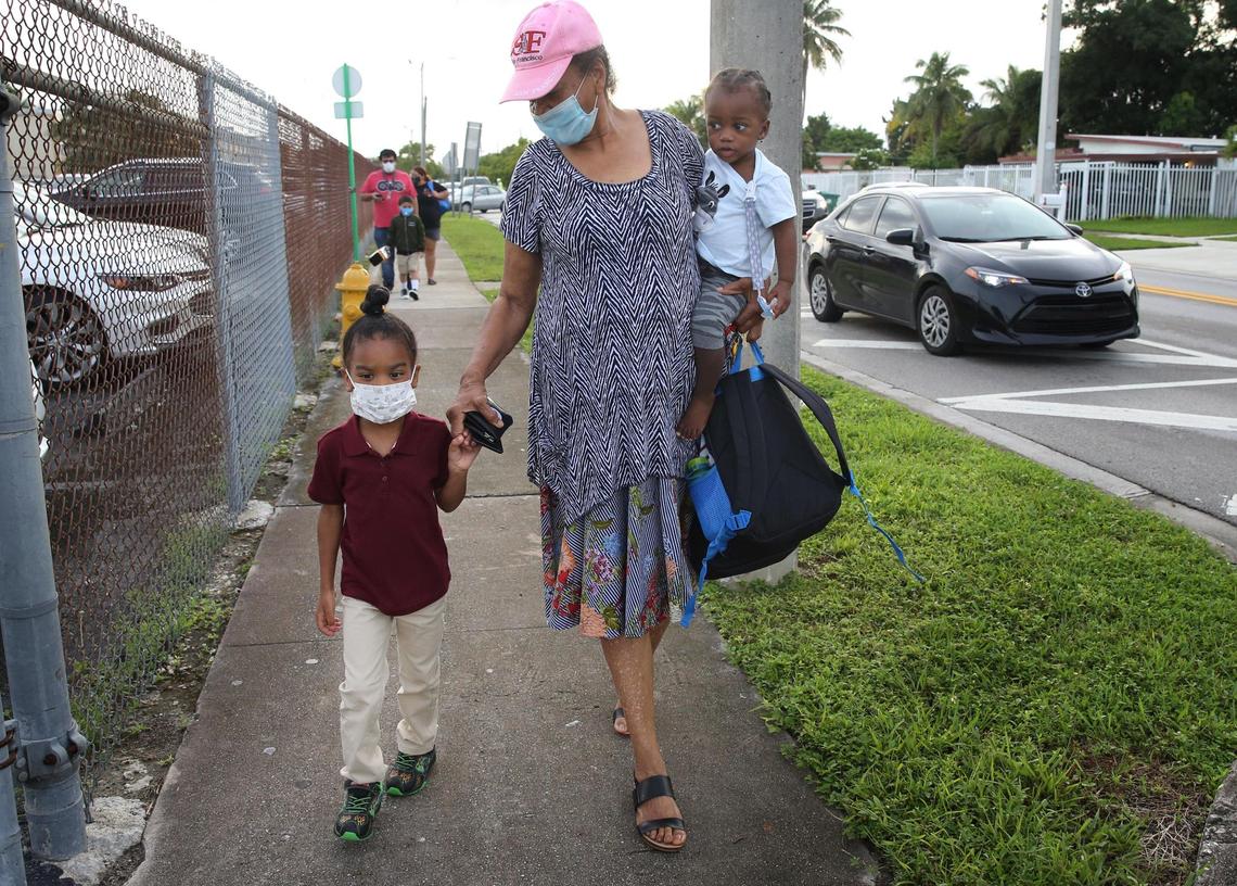 In Miami-Dade County students in pre-K, Kindergarten and first grade were welcomed back to schools Monday, October 5, 2020. Makai Walker, 5, holds hands with his great-grandmother, Yvonne Brooker, 77, as she carries Avery Walker as they walk Makai for his first day of school at Carrie P. Meek/Westview K-8.