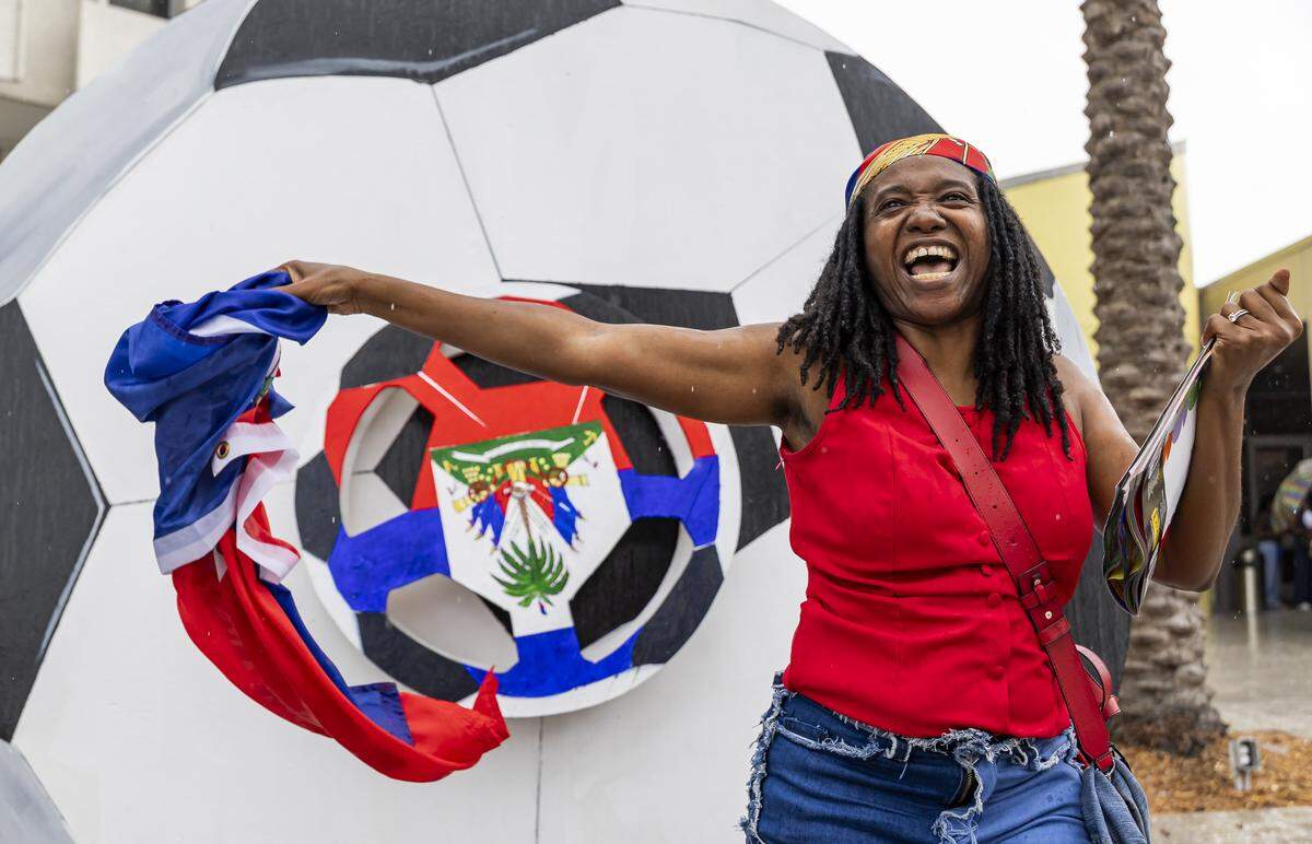 Odeline Paul waves her flag while waiting for a meet-and-greet with the Haiti national soccer team.