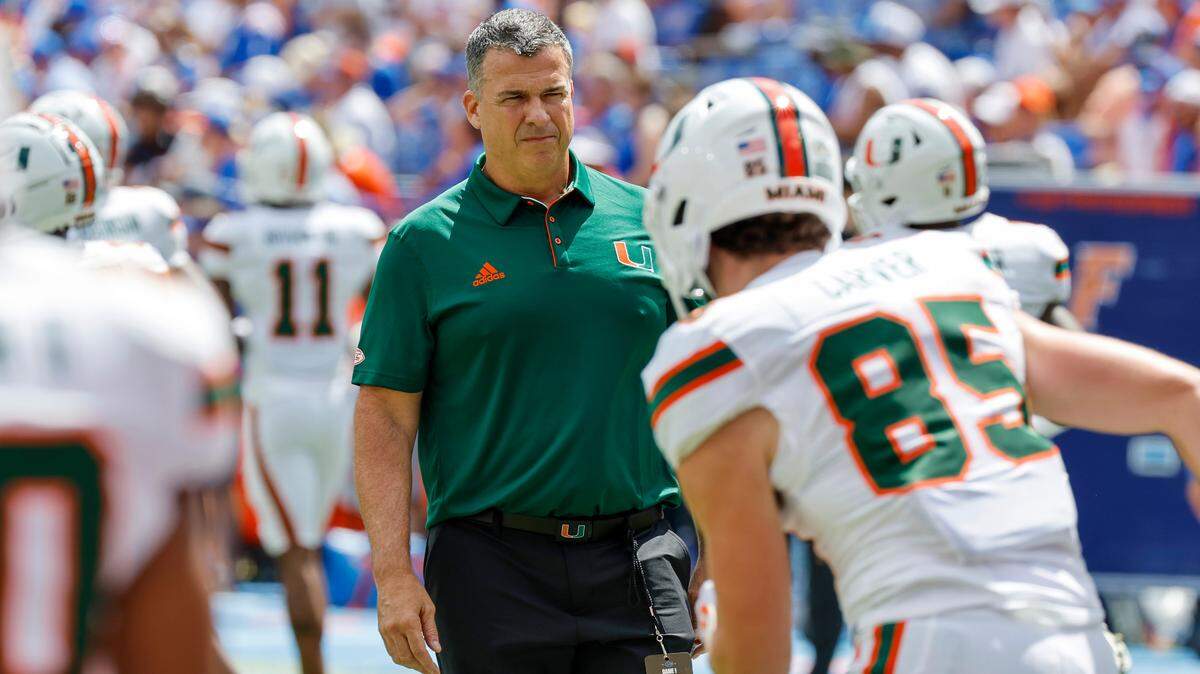 Miami Hurricanes head coach Mario Cristobal works with players on the field before the start of a NCAA college football game against the Florida Gators at Ben Hill Griffin Stadium in Gainesville, Florida, on Saturday, August 31, 2024.