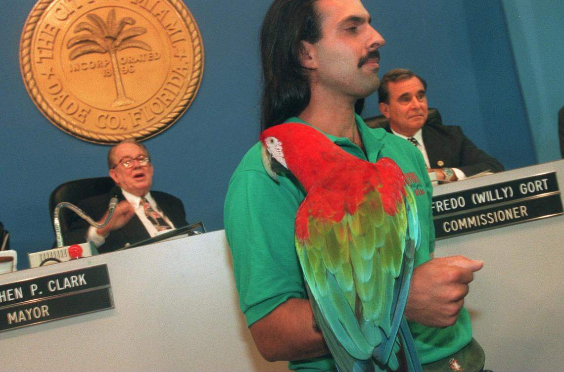In this file photo from Sept. 28, 1995, Eddie Lorenzo, then an animal trainer at the Parrot Jungle and Gardens, holds Bert, a green-winged macaw. In the backround are, left, Mayor Steve Clark and Commissioner Willie Gort. The Parrot Jungle made a presentation at the Miami City Commission meeting.