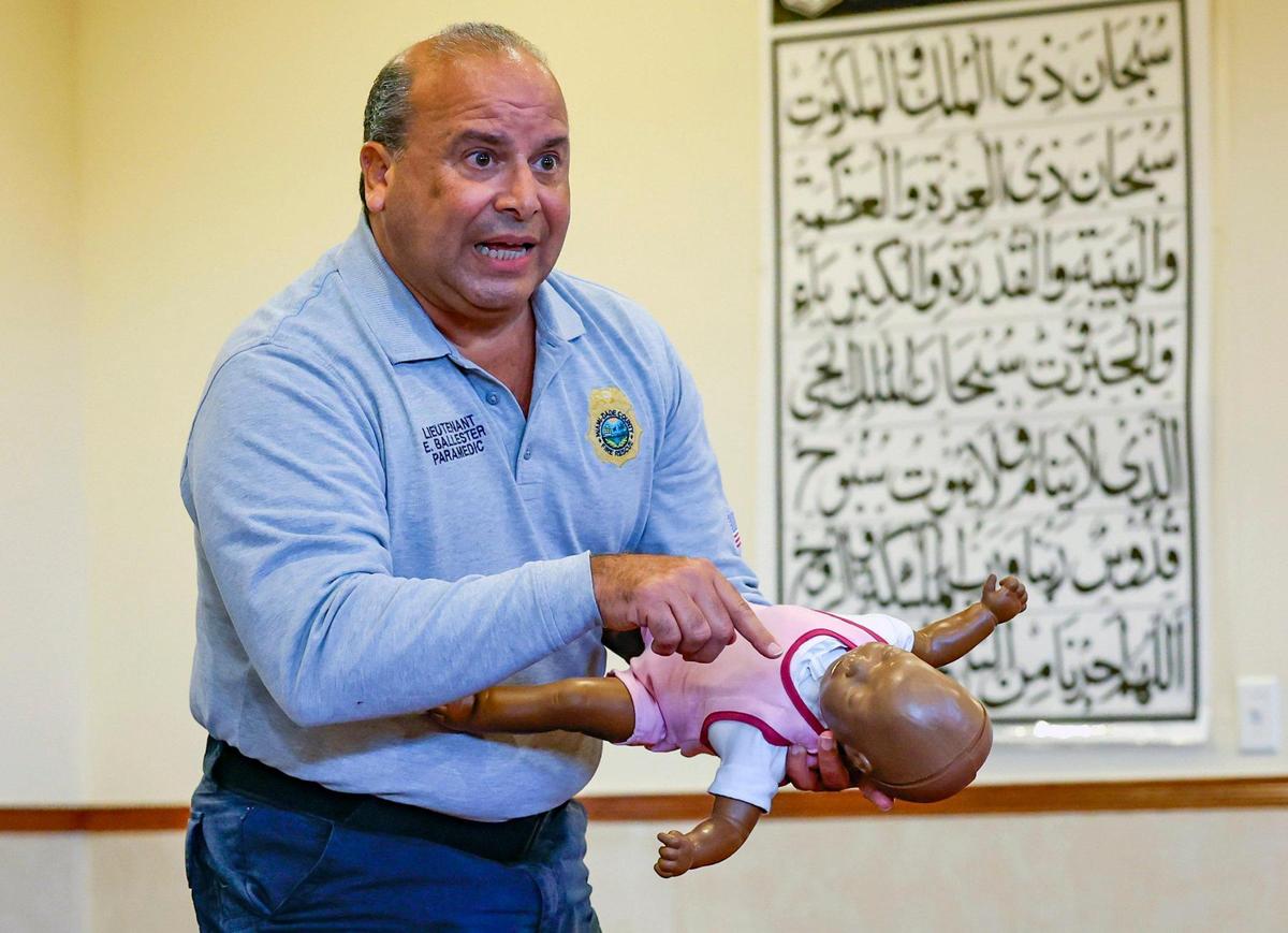Miami-Dade Fire Paramedic Lieutenant Eddy Ballester shows how to perform CPR chest compressions on an infant mannequin during a training session on how to respond to medical emergencies at the Islamic Center of Greater Miami-Masjid in Miami Gardens, Florida, Tuesday, June 27, 2023.