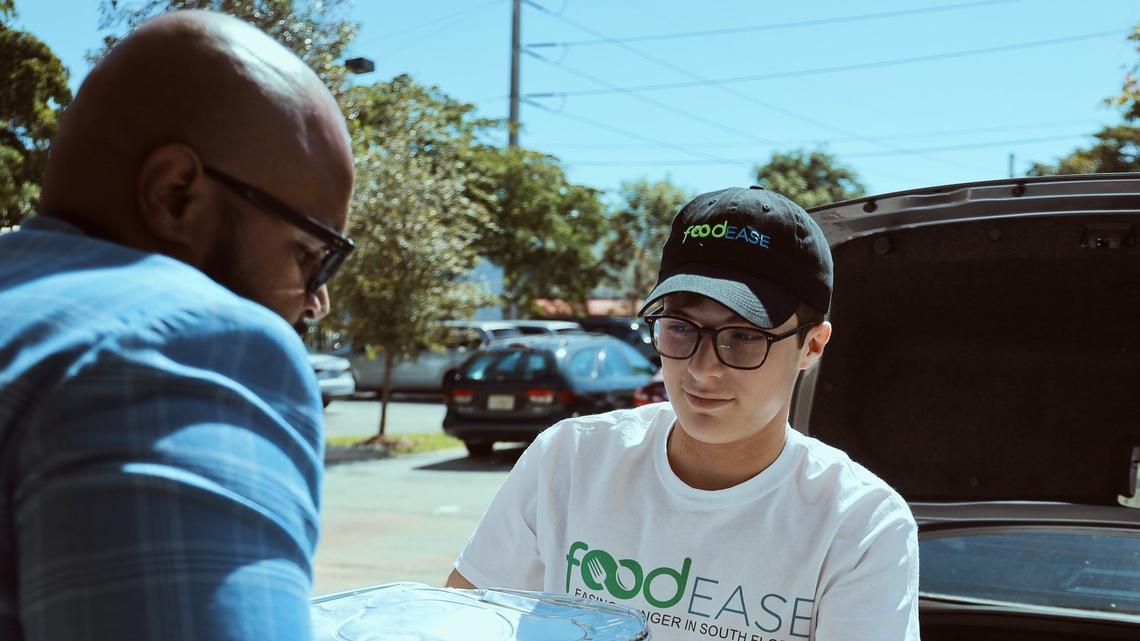 Henry Hurowitz, center, hands unused food from Super Bowl 54 to Ryon R. Coote, chief development officer of the Broward Partnership, a homeless services nonprofit in Fort Lauderdale. Hurowitz, 16, is the founder of foodEASE, a nonprofit that collects leftovers from local hospitality groups and delivers them to those in need.