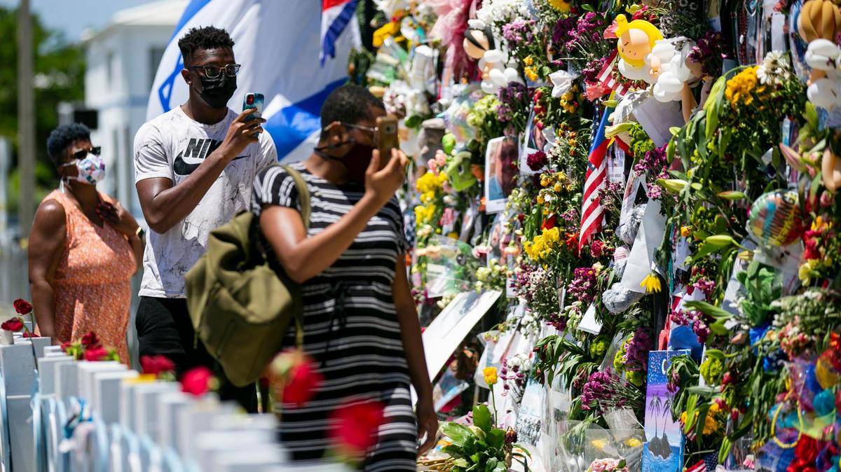 Philadelphia visitor Alexander Adeshigbin, second from left, walked along the Surfside memorial wall in July.