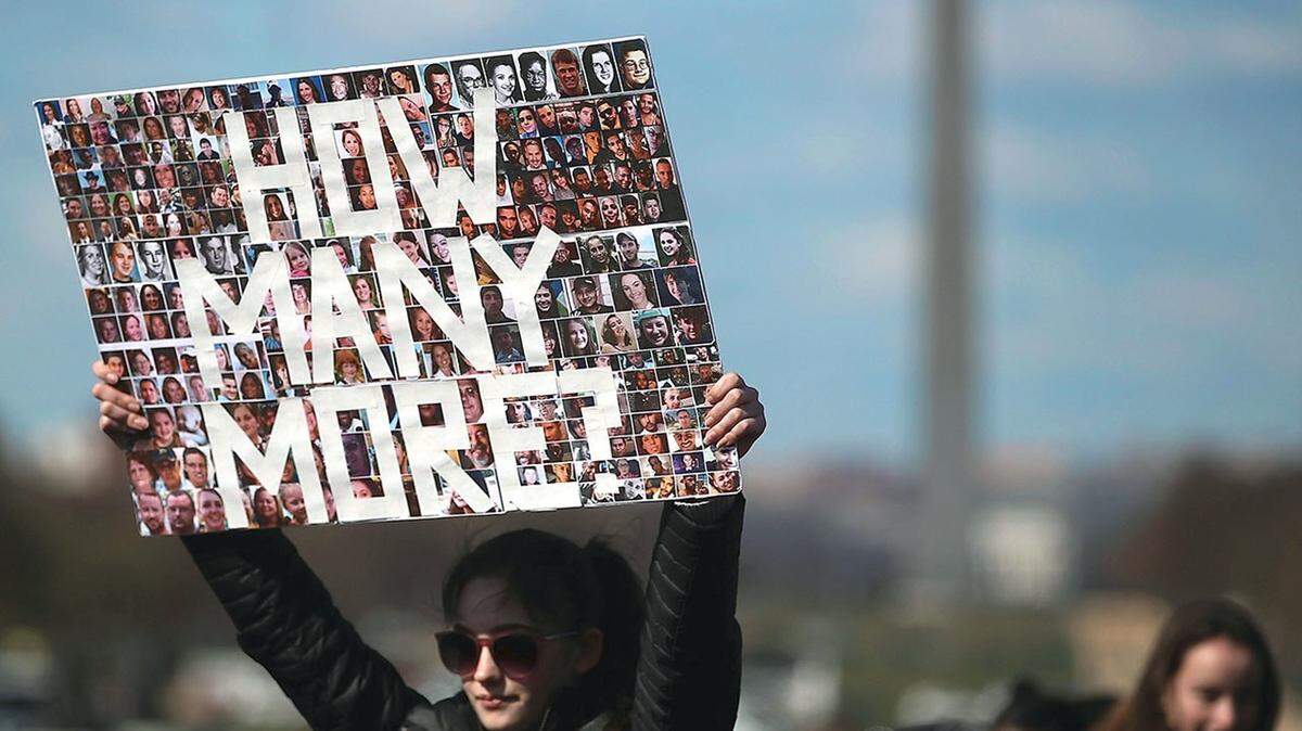 A year after the massacre at Marjory Stoneman Douglas High School in Parkland, young woman holds a sign to protest lack of action on gun control.