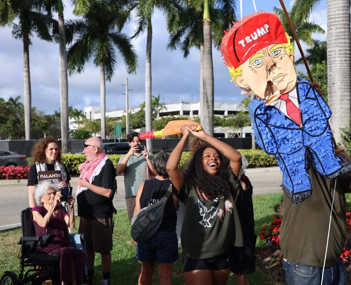 Organizer Britney Cooke of the Climate Defenders, take a swipe at the piñata of Donald Trump as a small group of protestors gathered around the mall entrance, wielding bright signs that conveyed messages calling for increased accountability and transparency from the tech giant on Tuesday, March 3, 2026 at the entrance of Aventura Mall in Aventura, Florida.