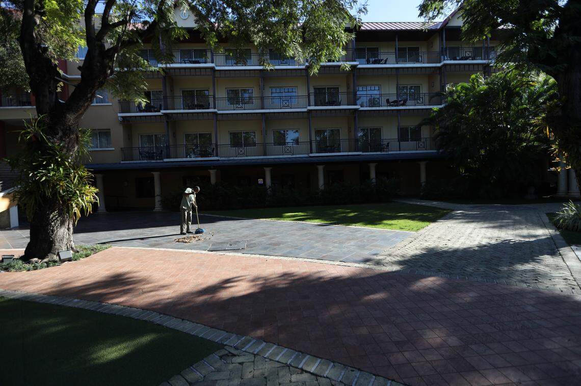 An employee sweeps leaves near the pool at the Karibe Hotel, which has laid off half of its staff because of cancellations.