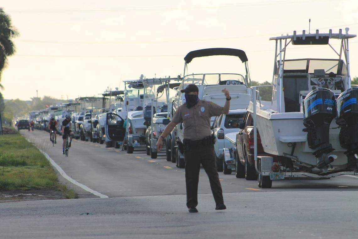 A Miami-Dade police officer directs traffic on Southwest 248th Street Saturday morning, May 2, 2020. Hundreds of people in cars and truck trailering boats waited to get into Blackpoint Marina.