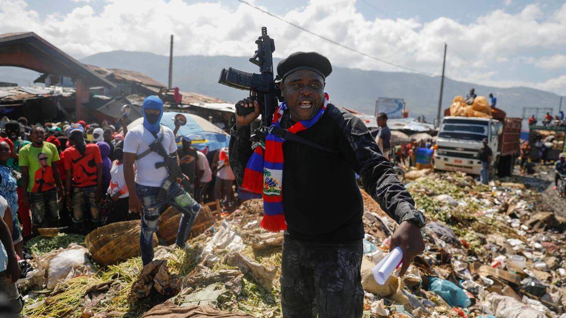 FILE - Jimmy Cherizier, also known as Barbecue, the leader of the “G9 and Family” gang, stands next to a garbage pile to call attention to the conditions people live in as he leads a march against kidnapping through La Saline neighborhood in Port-au-Prince, Haiti, Oct. 22, 2021. Cherizier is a former officer with Haiti’s National Police who worked with the Departmental Crowd Control Unit, which is deployed when there are riots or protests and has been accused of excessive force. He has since become whom many consider Haiti’s most powerful gang leader. (AP Photo/Odelyn Joseph, File)