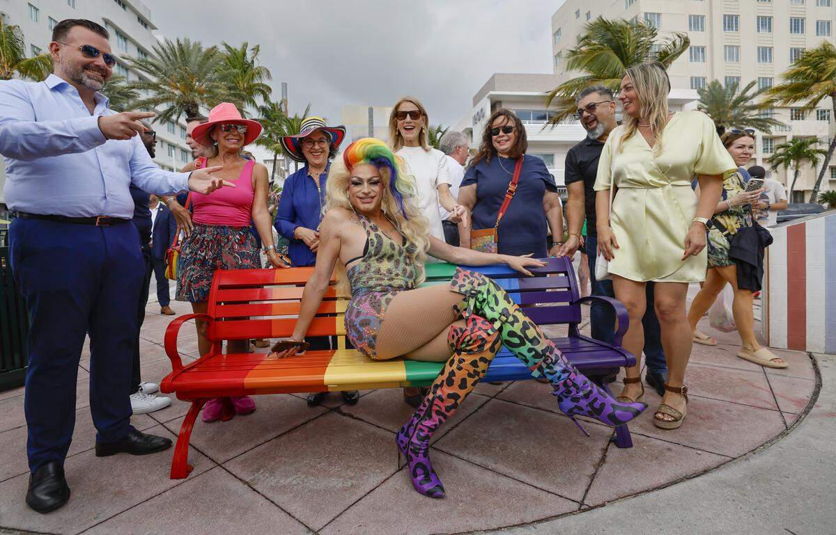 Performing Artist C.C. Glitzer sits on the rainbow colored bench as Miami Beach officials and community members gather in Lummus Park for the unveiling of a rebuilt LGBTQ+ crosswalk made of 3,606 colorful pavers on Friday, April 10, 2026. The installation was created less than six months after the Florida Department of Transportation removed the original crosswalk at 12th Street and Ocean Drive in Miami Beach, Florida.