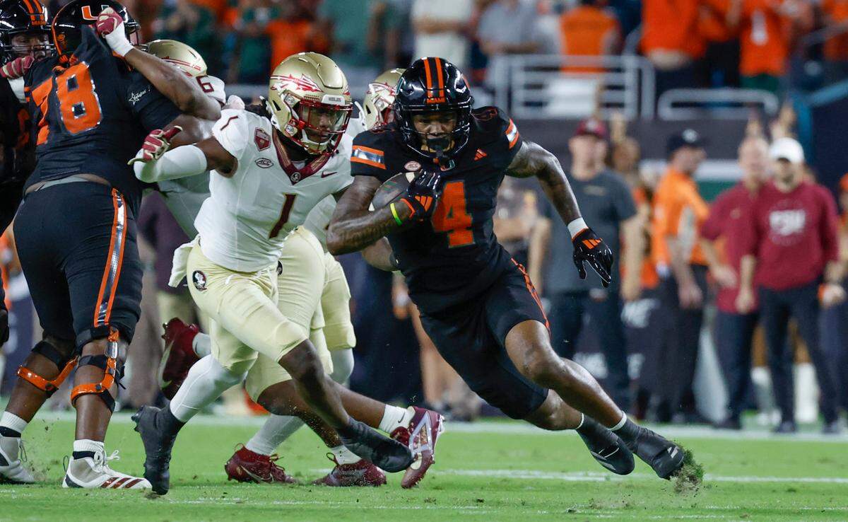 Miami Hurricanes running back Mark Fletcher Jr. (4) on a carry as Florida State Seminoles defensive back Charles Lester III (4) gives chase in the first half during an NCAA football game at Hard Rock Stadium in Miami Garden, Florida on Saturday, October 26, 2024.