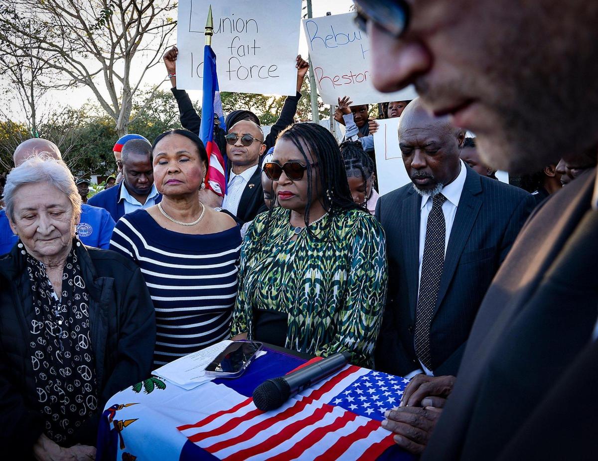 Miami-Dade Commissioner Marlene Bastien, center, lead in a moment of silence at 4:53 PM. Members of the Haitian community and others gathered at Toussaint L’ Ouverture Statue for the customary moment of silence occurring at 4:53PM – the time of the 2010 earthquake prior to leading a procession to the Little Haiti Cultural Complex for a ceremonial remembrance of those who perished on Sunday, December 12, 2025.