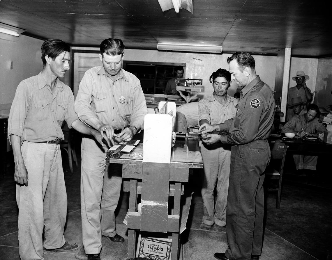 Two Mexican immigrants, Pedro Vidal, left, and Canuto Garcia, right, are fingerprinted by U.S. Border Patrol inspectors Paul Watson, left, and N. Franklin Davidson, right, at a detention camp at El Centro, Calif., on Aug. 11, 1951. After processing they would be airlifted back to their homes in Sinaloa, Mexico.