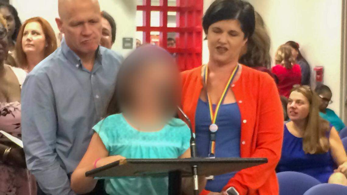 ‘Daisy’ flanked by her parents, Jessica and Gary Norton, at a Broward School Board meeting in 2017 where she told Board members how glad she felt to be in a school district where transgender students were supported.