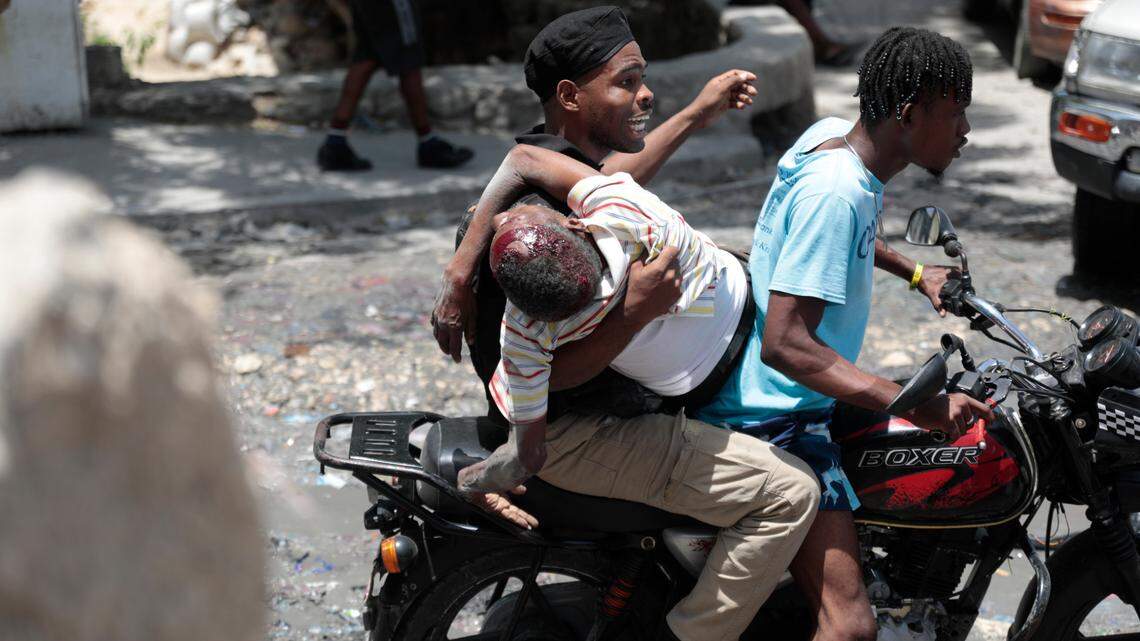 A police officer riding a moto-taxi transports a shooting victim in the Carrefour-Feuilles district of Port-au-Prince, Haiti, on Tuesday, Aug. 15, 2023.