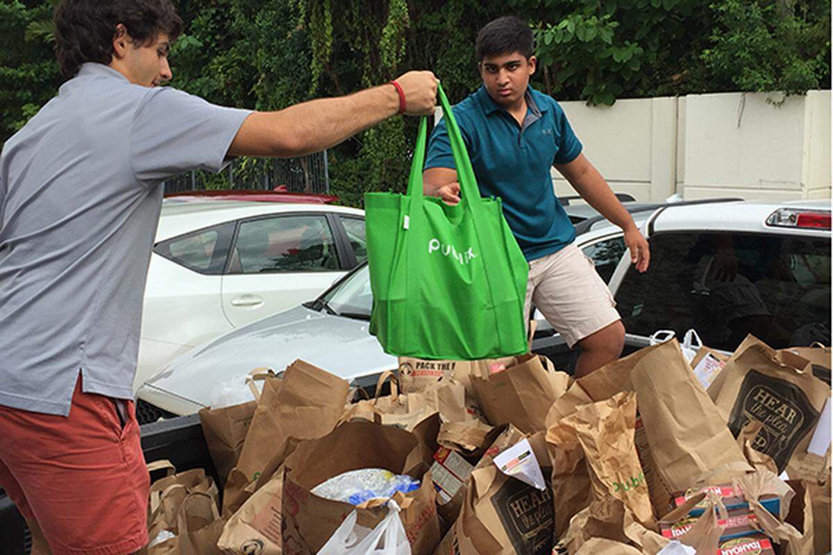 Ransom Everglades School students recently donated groceries, turkeys, hams, water, and pumpkin cookies, donated by The Fresh Market, to the Miami Rescue Mission for families in need this Thanksgiving holiday. From left, Ben Cobb and Nikhil Seshadri packed trucks with all donated goods.