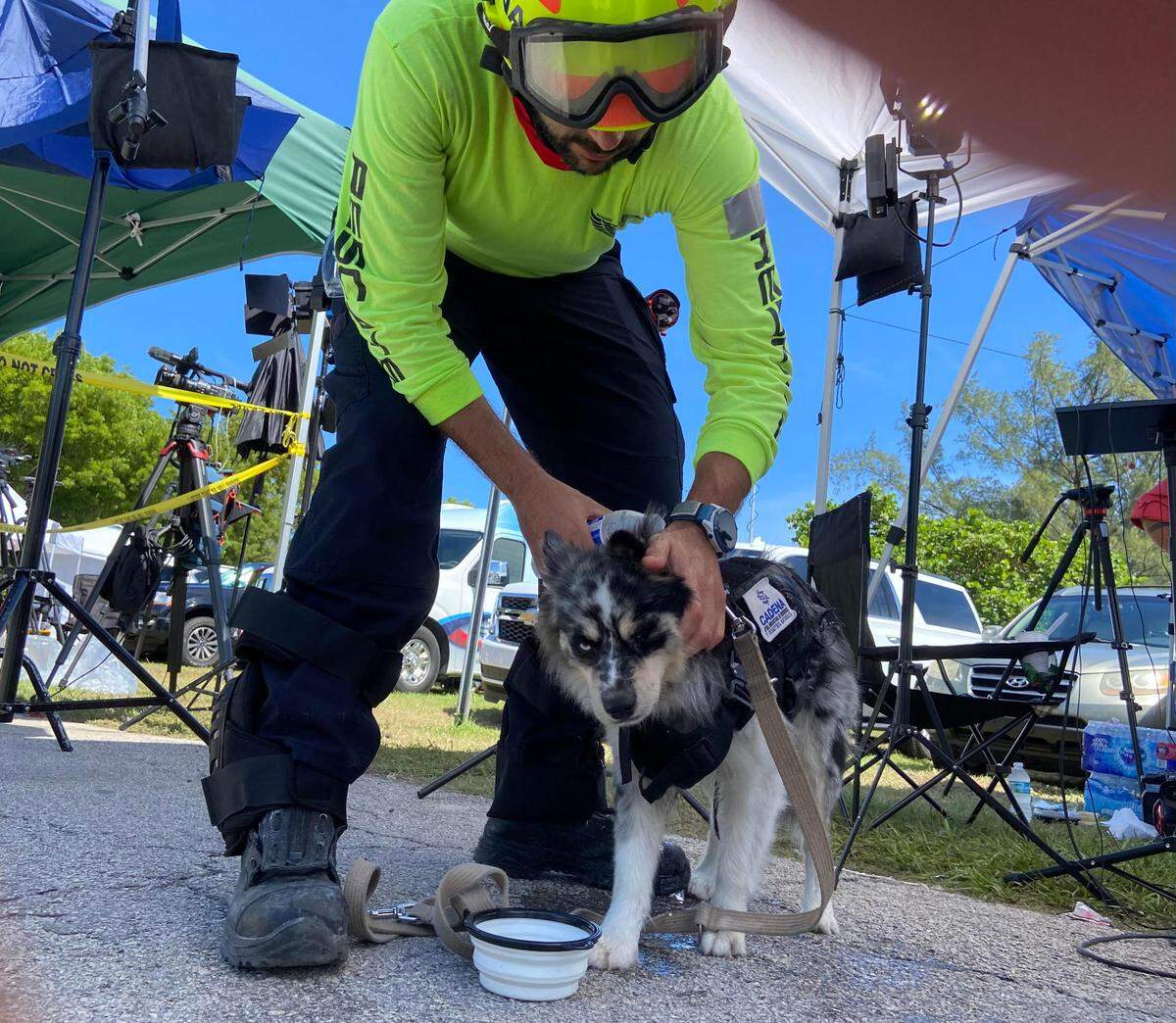 Moises Soffer, a volunteer rescuer with Cadena International, cools down Oreo, a dog trained to recover living victims, on Sunday, June 27, 2021, near the scene of the Champlain Towers collapse in Surfside, Florida.