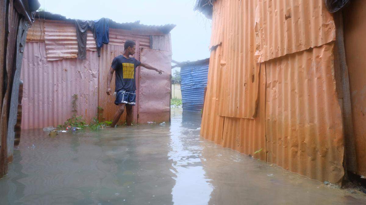 A man walks between houses flooded by the rains of Tropical Storm Franklin, along the Ozama River in the Gualey neighborhood of Santo Domingo, Dominican Republic, Wednesday, Aug. 23, 2023.