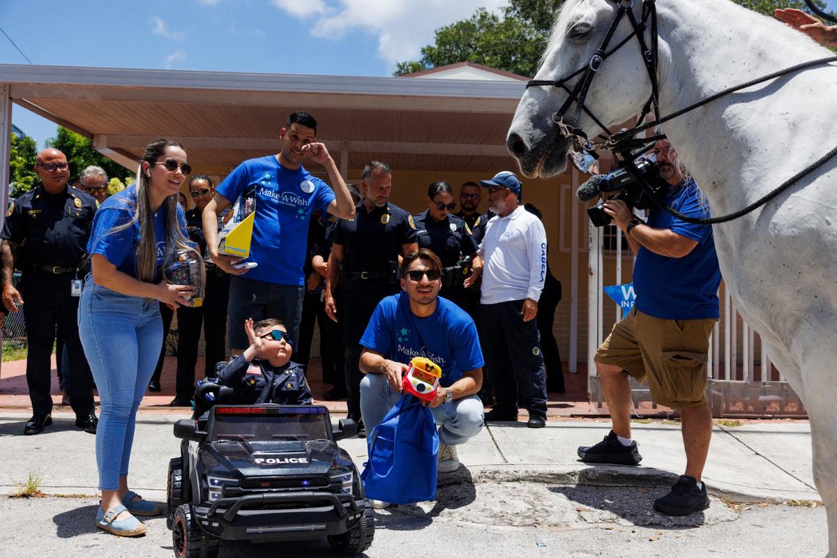 Franco Bernal, center, 6, battling childhood leukemia, waves to a City of Miami Police horse during his Wish Reveal announcing his trip to Disney World on Thursday, July 18, 2024, with a parade by Make-A-Wish and City of Miami Police in Miami.