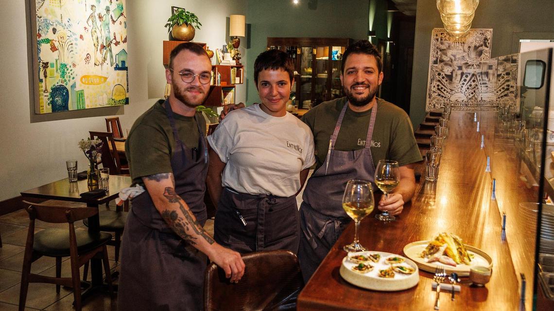 Chefs Evan Burgess (left) and Osmel Gonzalez with waitress Stefani de Souza display grilled Sebastian oysters and a tempura-fried crispy salad at EntreNos, a new restaurant open at night inside Tinta y Cafe in Miami Shores.