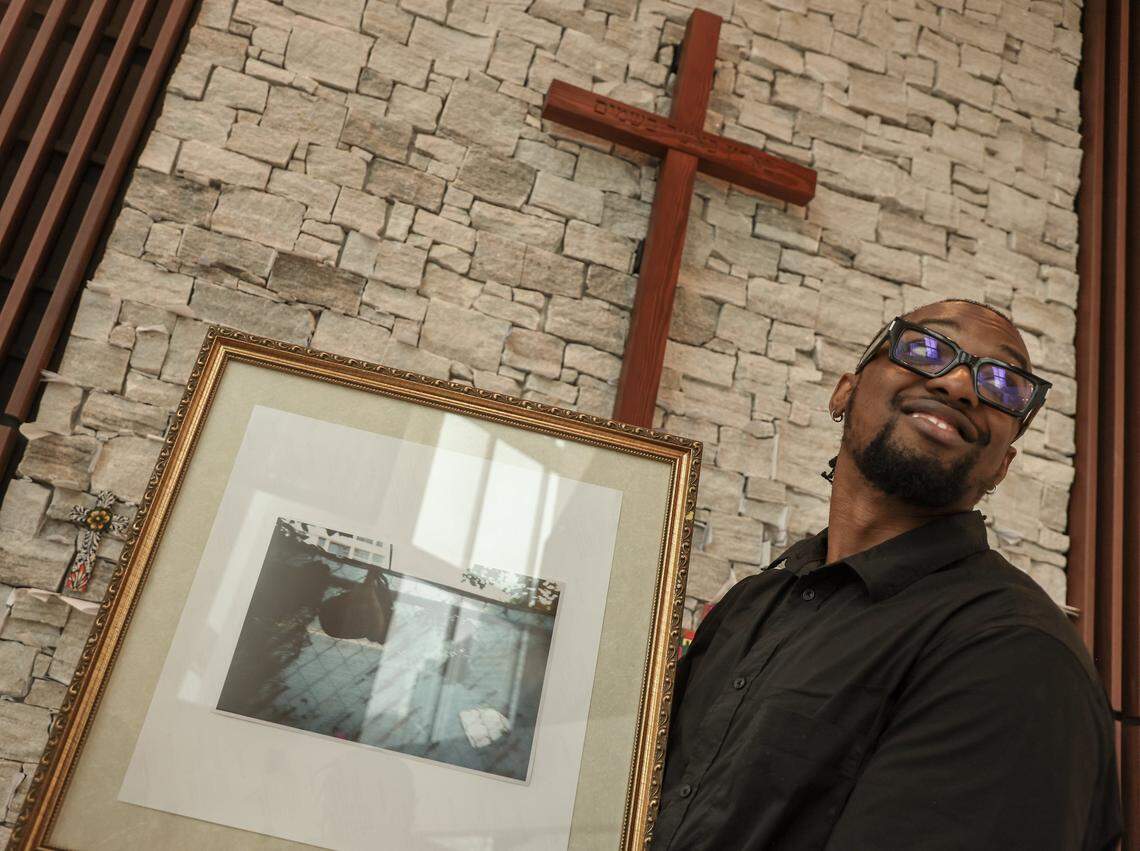 Curatorial director Nyya Toussaint proudly holds the framed artwork for installation as four high school students installed photos inside the First Church Miami coffee shop for the exhibition Sparrow, featuring the photography of local photographers navigating homelessness under the artistic direction of Miami-based artist Christopher Mitchell on Sunday, November 30, 2025.