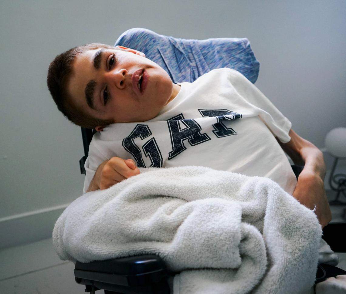 Charles watching cartoons on his TV. His mother must lift him out of bed and put him in his wheelchair.