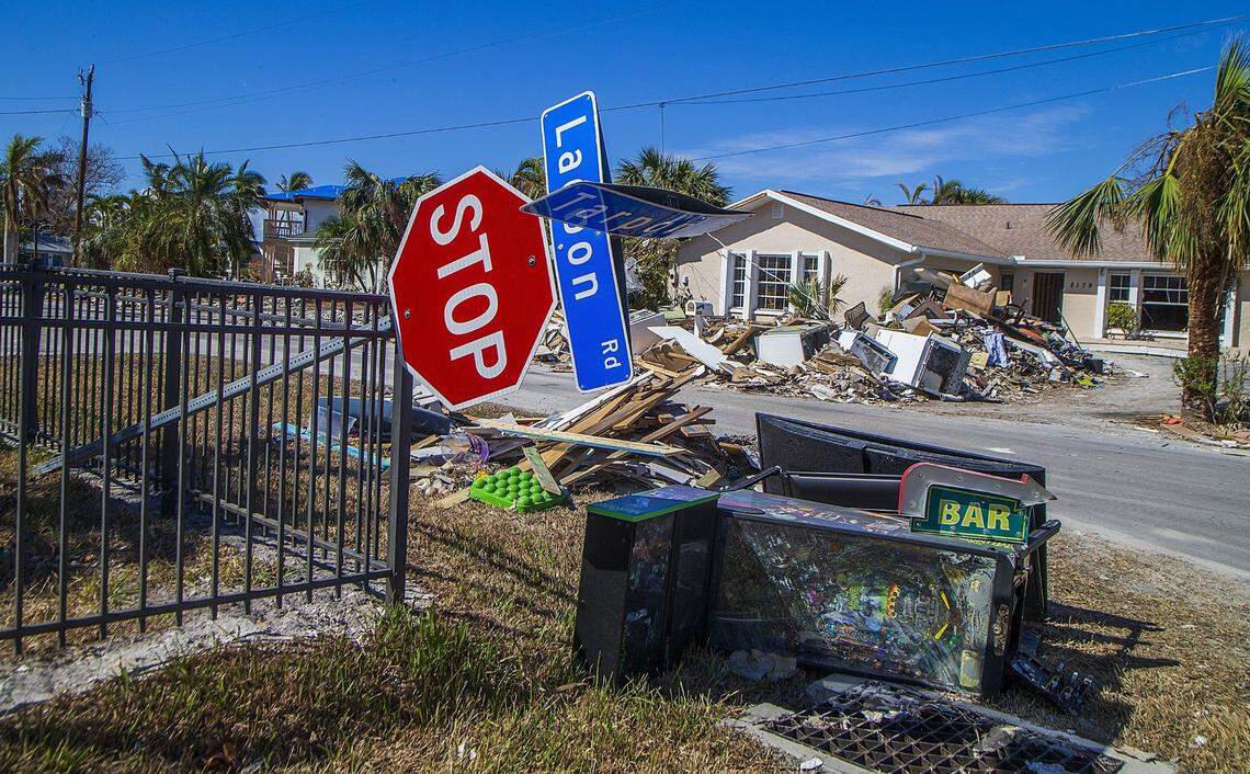 A downed stop sign rests on a fence on the corner of Lagoon and Tarpon roads in Fort Myers Beach, next to items like a pinball machine and appliances, Wednesday, Oct. 26, 2022. The items were among tons of debris left behind in the aftermath of Hurricane Ian, which hit the area as a Category 4 storm a month earlier.