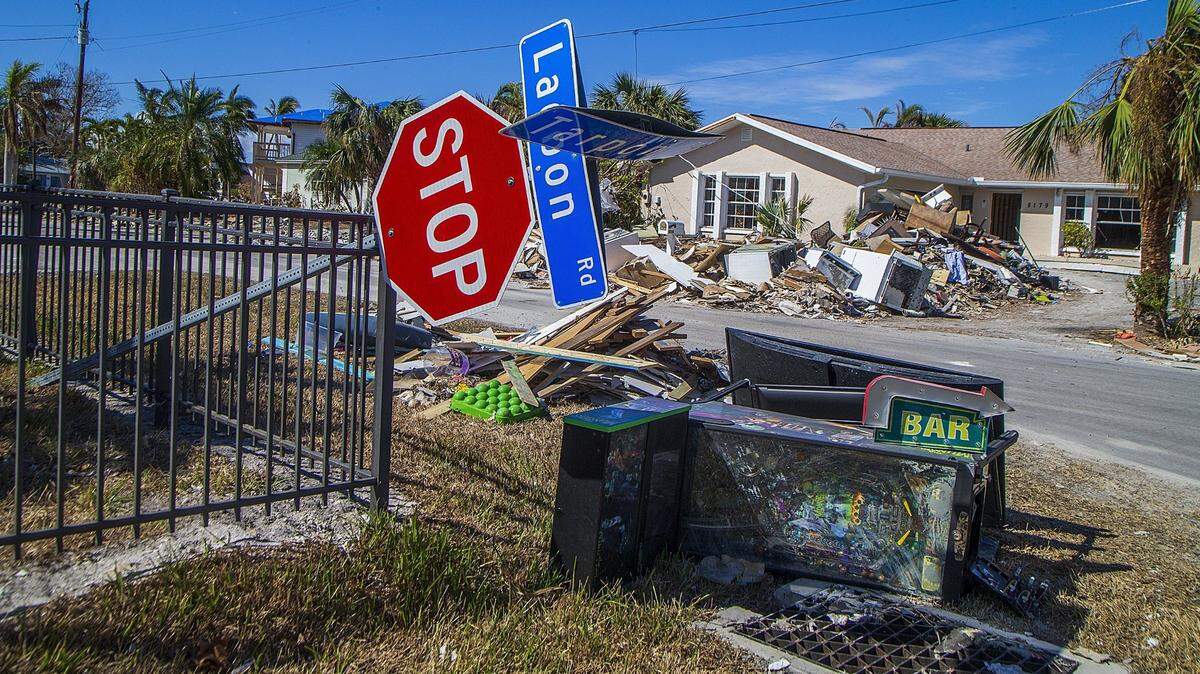 Un letrero de pare derribado descansa sobre una cerca en la esquina de las carreteras Lagoon y Tarpon, en Fort Myers Beach, junto a objetos como una máquina de pinball y electrodomésticos, el miércoles 26 de octubre de 2022..