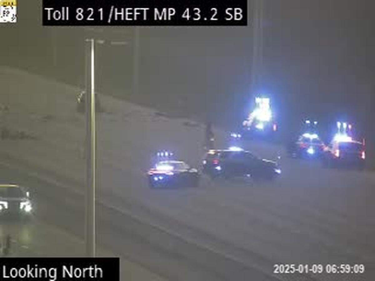 Some of the car parts from the crash can be seen beyond the Florida Highway Patrol troopers.