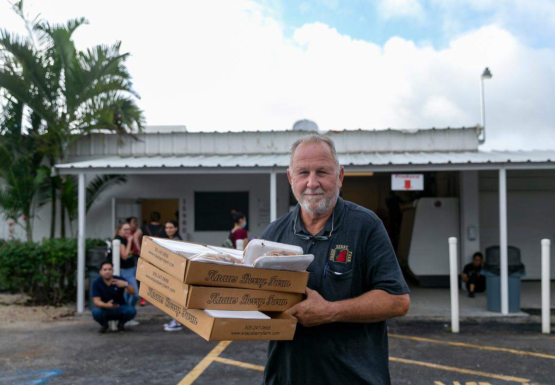 Herb Grafe, who has been working at Knaus Berry Farm for almost 47 years, helps load a customer’s vehicle with freshly baked cinnamon rolls and other goods during their opening day in Homestead, Florida, on Tuesday, Oct. 26, 2021.