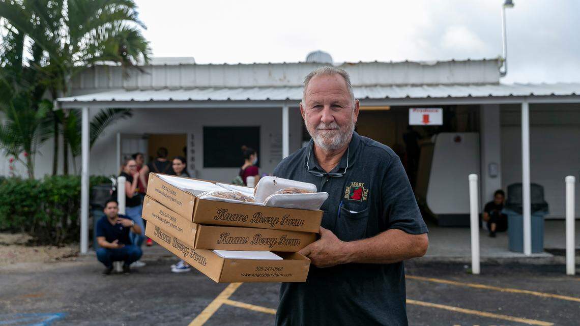 Herb Grafe, who has been working at Knaus Berry Farm for almost 47 years, helps load a customer’s vehicle with freshly baked cinnamon rolls and other goods during its opening day, Tuesday, Oct. 26, 2021, in Homestead, Florida.