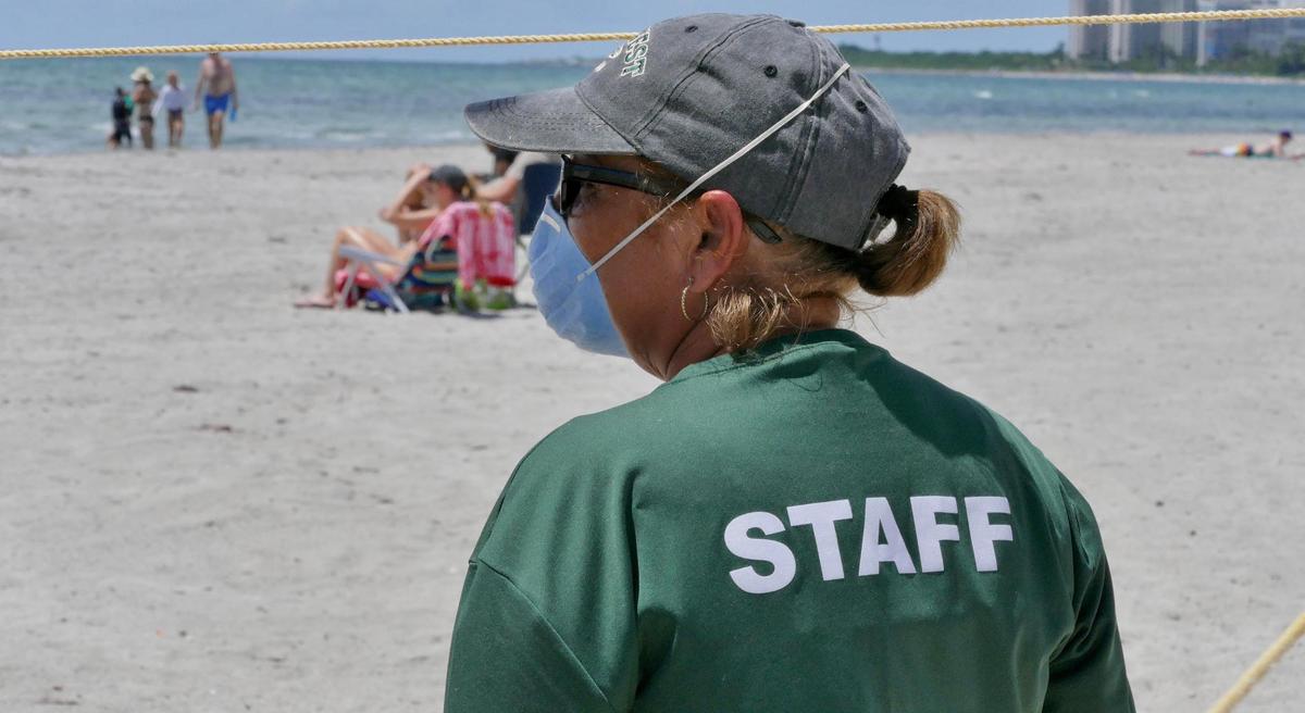 Marina Silverman, one of the newly hired patrols working the beach at Crandon Park keeps an eye on beachgoers to make sure they are following the new rules.