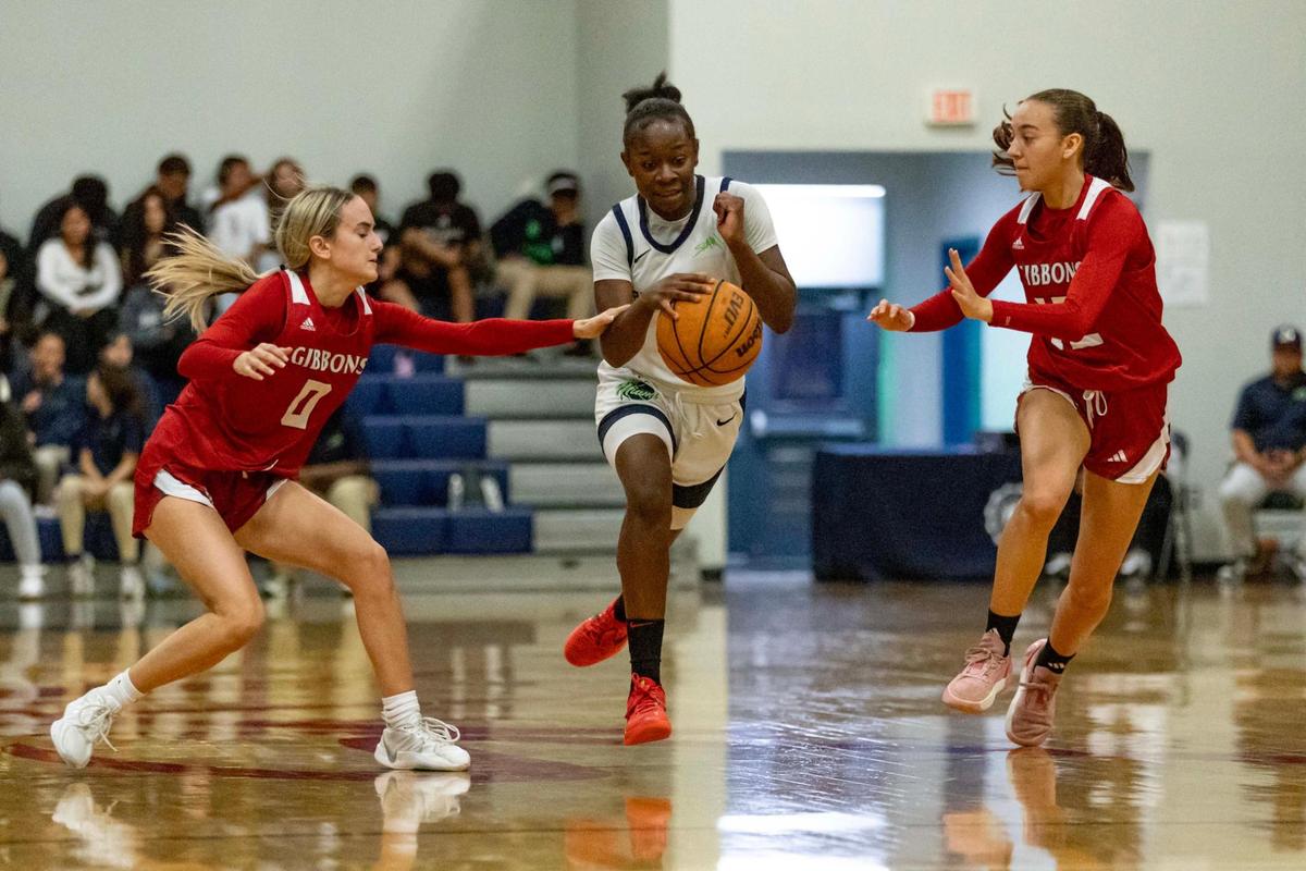 SLAM! guard Jim’Miyah Branton (12) splits the defense as she dribbles between Cardinal Gibbons defenders Sav Nicholson (0) and Maddie Kornowski (12) during the girls basketball regional semifinal playoff game on Tuesday, February 18, 2025, in Miami, Florida.