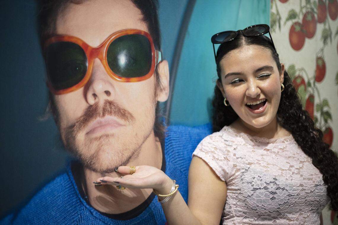 Celine Fernandez poses beside a photo of singer Harry Styles at a pop-up shop celebrating the release of Harry's House and his upcoming tour in the Wynwood neighborhood of Miami on Friday, March 6, 2026. The temporary shop features exclusive merchandise, album displays and themed installations tied to the singer's latest release and tour.