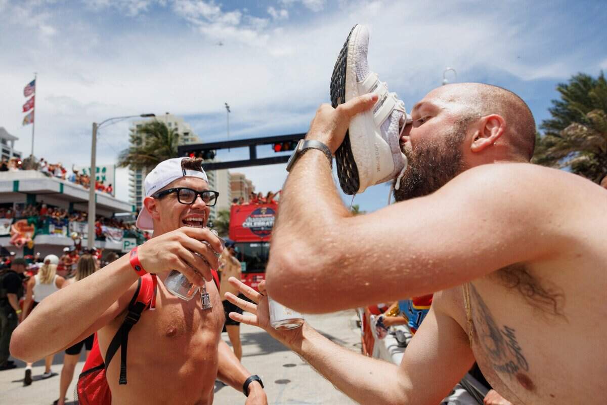 Florida Panthers center Evan Rodrigues (17) watches a fan drink beer out of his shoe during the Florida Panthers Stanley Cup Championship victory parade on Sunday, June 22, 2025 down Las Olas in Fort Lauderdale, Fla.