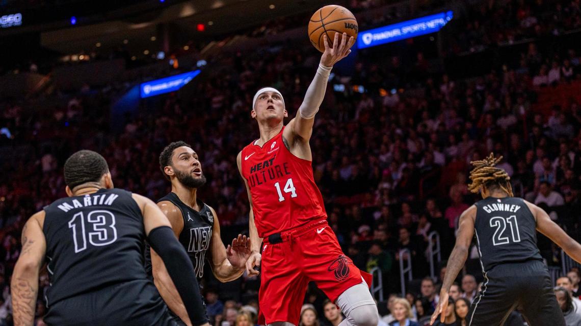 Miami Heat guard Tyler Herro (14) rises above Brooklyn Nets guard Ben Simmons (10) as he lays up the ball during the first half of an NBA game at the Kaseya Center on Monday, Dec. 23, 2024, in Miami, Fla.