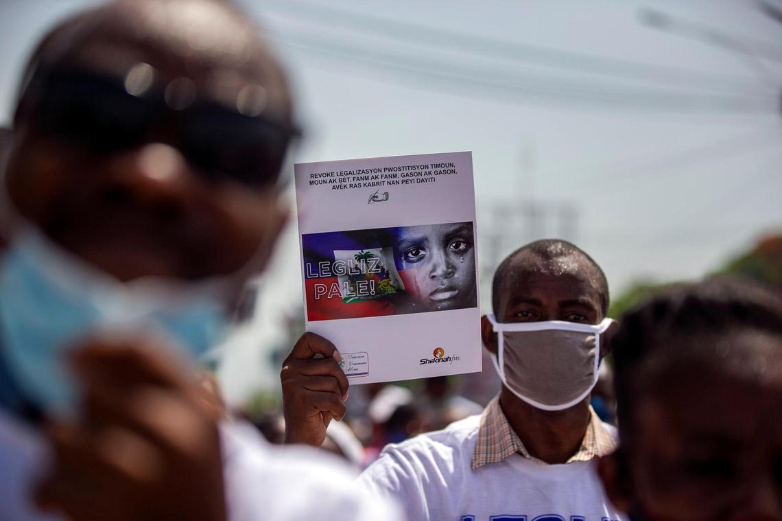 A protester holds a print out of the Change.org petition demanding that Haitian President Jovenel Moise rescind a decree rewriting Haiti’s 1835 penal code. Protesters marching against gay rights in Port-au-Prince, Haiti, Sunday, July 26, 2020 say the code now recognizes same-sex unions and tacitly allows homosexuality. The government says it does not.