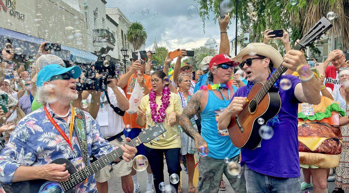 Musicians guide marchers in singing the late Jimmy Buffett’s “Margaritaville” Sunday, Sept. 1, 2024, in Key West, Fla., during a second-line procession celebrating the life of the singer/songwriter who died Sept 1, 2023. From left: Florida Keys troubadour Howard Livingston; Key West Mayor DeeDee Henriquez; and Will Kimbrough, a Buffett collaborator and co-writer of his posthumous single, “Bubbles Up.” The procession was a highlight of the “Just a Few Friends Key West” festival memorializing Buffett, who called the island home during some of his most productive years.