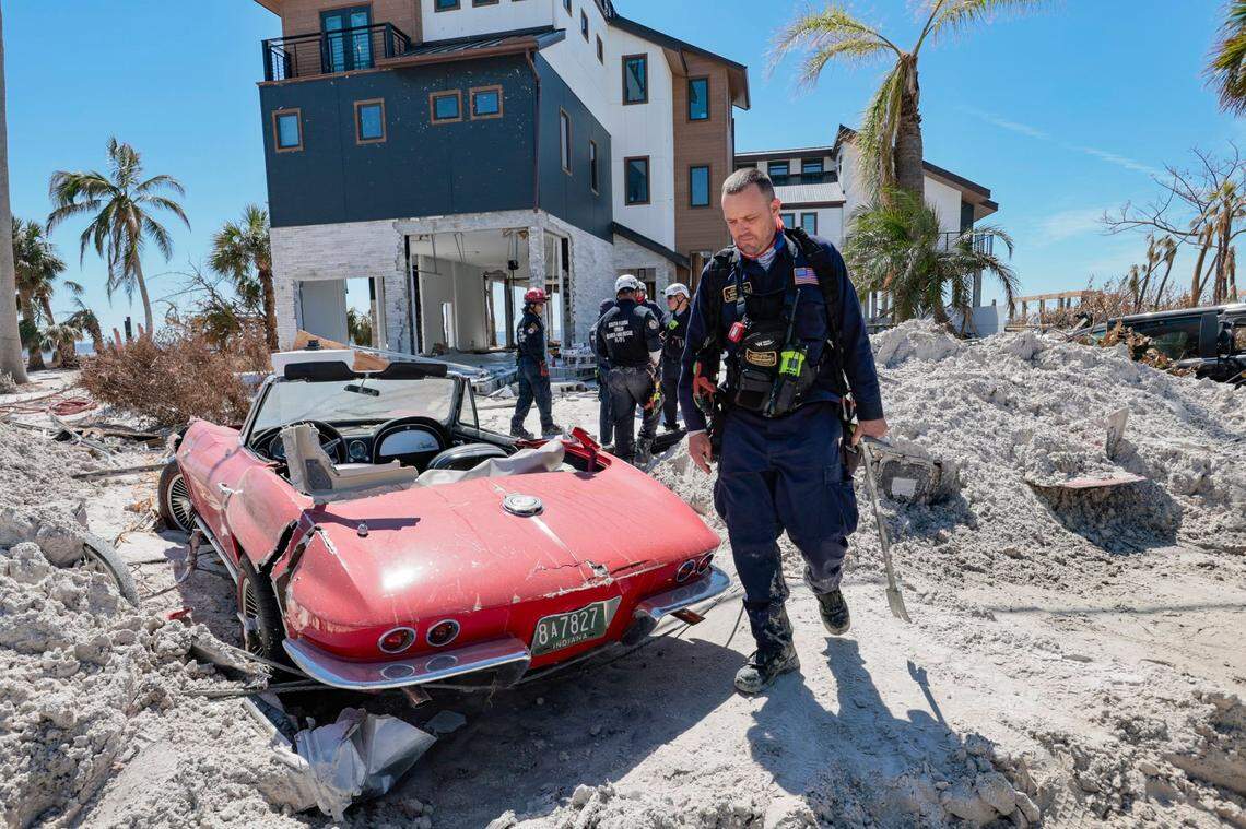An Urban Search and Rescue Florida Task Force 2 team member walks past a 1965 Corvette damaged by flood waters caused by Hurricane Ian on Fort Myers Beach on Monday, Oct. 3, 2022.