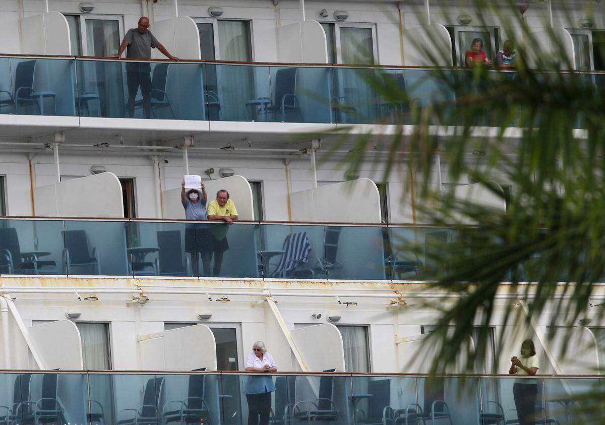 Coral Princess passenger holds a sign that reads “Let Me Go” as she and other passengers stand on their balconies. Miami-Dade Fire Rescue ambulances and fire trucks responded to the Coral Princess cruise ship at PortMiami Sunday, April 5, 2020, to help evacuate sick passengers.