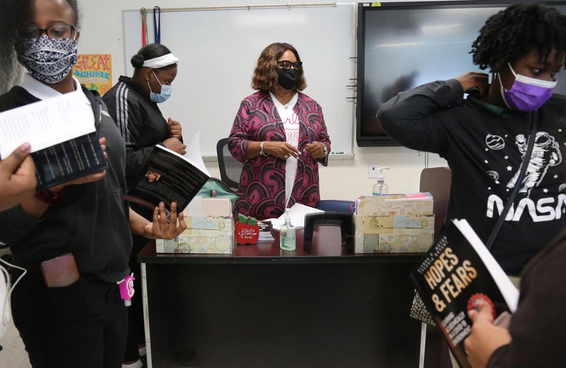 Ninth-grade students Ashley Joseph, Chenaya Gerifin and Devonne Malcom look over the books their teacher Glenda Moton, center, at North Miami Senior High recently had published: “Hopes and Fears: Learning Academically in a COVID-19 Environment.”